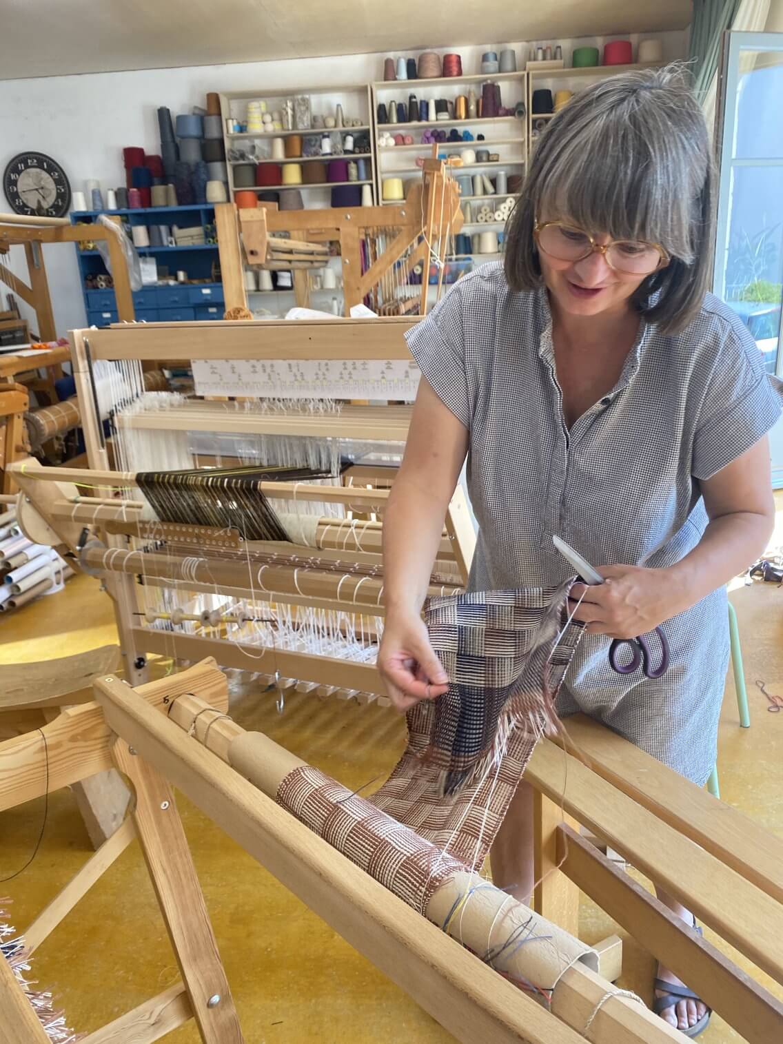 Fin du tissage, une élève retire son tissage du métier avec des ciseaux.
